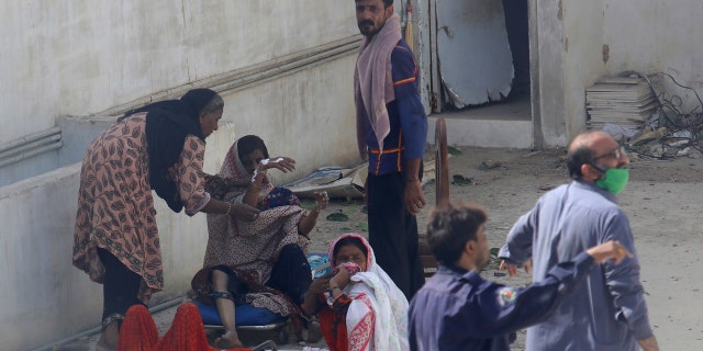 Residents of an area hit by a plane crash wait for medical help in Karachi, Pakistan, Friday, May 22, 2020.