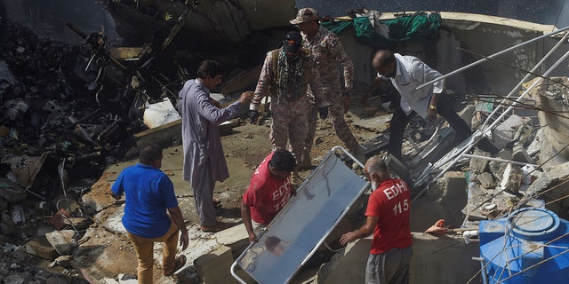 Rescue workers gather at the site after a Pakistan International Airlines flight crashed in a residential neighbourhood in Karachi on May 22, 2020. 