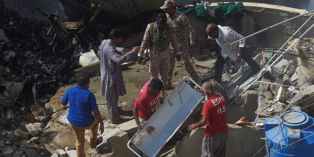 Rescue workers gather at the site after a Pakistan International Airlines flight crashed in a residential neighbourhood in Karachi on May 22, 2020. 