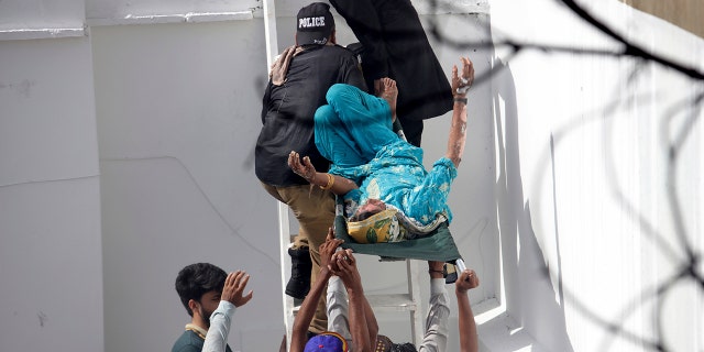 Volunteers carry an injured person at the site of a plane crash in Karachi, Pakistan, Friday, May 22, 2020.