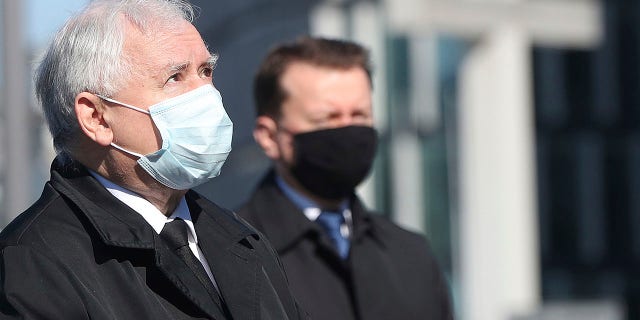 Poland's ruling party leader Jaroslaw Kaczynski, left, and a member of the ruling party, wearing a mask, pray at the monument to the late President Lech Kaczynski, the party leader's twin, killed with 95 others in a plane crash April 10, 2010 in Russia, on Sunday in Warsaw. Poland was to hold presidential election Sunday but the anti-coronavirus lockdown and political infighting made it impossible and there is no voting. (AP Photo/Czarek Sokolowski)
