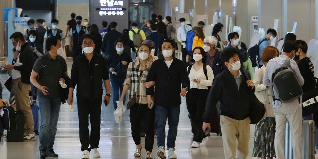 People wearing face masks arrive at the domestic flight terminal of Gimpo airport in Seoul, South Korea, on Wednesday. The quarantine authorities on Wednesday began to require all airplane passengers to wear masks amid the coronavirus pandemic. (AP Photo/Ahn Young-joon)