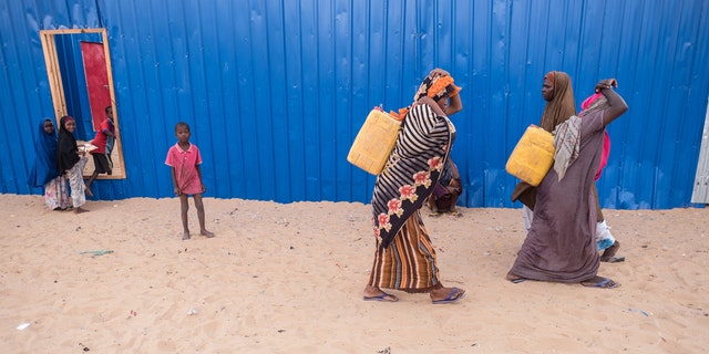 Women carrying jerrycans with water in IDP camp. Somalia in the grip of an unprecedent and devastating food crisis. Drought has caused crops to fail and cattle to die in Somalia causing severe food and water shortages. Brutal conflicts in South Sudan, Yemen and Nigeria and Somalia have driven millions of people from their homes and left millions more in need of emergency food. In Somalia, where cholera outbreaks have killed hundreds of people, the looming famine threatens 6.2 millionmore than half the population. It threatens to bring back the grim reality of 2011, when 260,000 Somalis starved to death. For over two decades, Somalia has been in a state of complex humanitarian crisis, with socio-economic, political and environmental factors leading to widespread conflict, drought, more recently flooding and numerous other recurrent human and natural disasters. In recent days, thousands of Somalis have trekked to Mogadishu desperately searching food and aid. (Photo by Maciej Moskwa/NurPhoto via Getty Images)