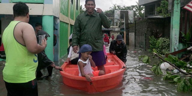 Residents ride a boat along a flooded village as typhoon Vongfong passes by Sorsogon province, northeastern Philippines on Friday May 15, 2020.