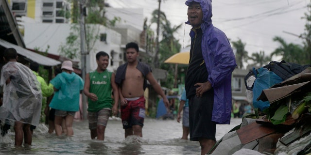 Residents wade along a flooded village caused by typhoon Vongfong as it passed by Sorsogon province, eastern Philippines on Friday May 15, 2020.