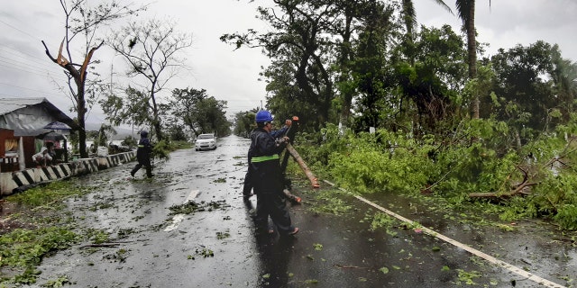Workers clear a road of trees and branches toppled by strong winds from typhoon Vongfong as it passes by Sorsogon province, eastern Philippines on Friday May 15, 2020.