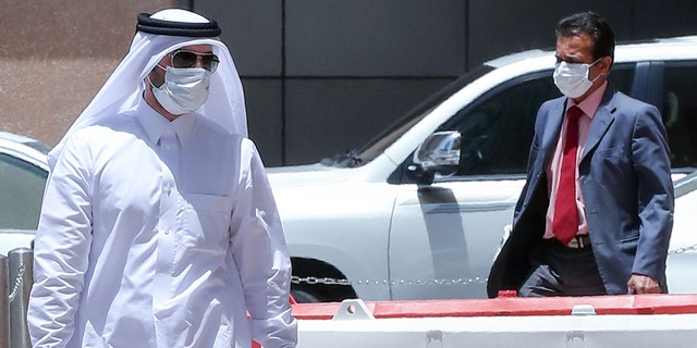 Men wearing protective masks walk by in Qatar's capital Doha, on May 17, 2020, as the country begins enforcing the world's toughest penalties for failing to wear masks in public, as it battles one of the world's highest coronavirus infection rates. - More than 30,000 people have tested positive for COVID-19 in the tiny Gulf country, 1.1 percent of the 2.75 million population, although just 15 people have died. Violators of the new rules will face up to three years in jail and fines of as much as $55,000. (Photo by KARIM JAAFAR / AFP) (Photo by KARIM JAAFAR/AFP via Getty Images)