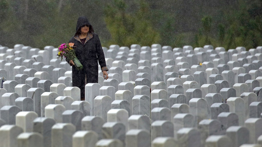 A woman looks for a grave in the rain as she visits Cape Canaveral National Cemetery for Memorial Day