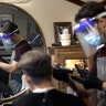 Vin Norton gets his hair cut by barber Cristian Lopez at Barber Walter's barbershop as they both wear masks in Wellesley, Mass. May 26, 2020. 