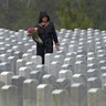 A woman looks for a grave in the rain as she makes a Memorial Day visit to Cape Canaveral National Cemetery in Mims, Fla., May 25, 2020. 