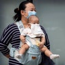 A woman and child wearing masks to help protect against the coronavirus stand out on the streets of Beijing, May 13, 2020. 
