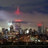 Low clouds float through midtown Manhattan past the Empire State Building lit in red to honor COVID-19 health care workers in New York City, May 27, 2020.