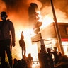 Protestors demonstrate outside of a burning fast food restaurant, Friday, May 29, 2020, in Minneapolis. Protests over the death of George Floyd, a black man who died in police custody Monday, broke out in Minneapolis for a third straight night.