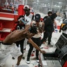 In this Wednesday, May 27, 2020 photo, a looter uses a claw hammer as he tries to break into a cash register at a Target store in Minneapolis. Rioters ignited fires and looted stores all over the city, as peaceful protests turned increasingly violent in the aftermath of the death of George Floyd.