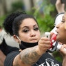 Ashley Quinones holds the microphone for a woman who declined to give her name as protesters called for Hennepin County Attorney Mike Freeman to press charges against Minneapolis police officers in the death of George Floyd earlier in the week, Wednesday, May 27, 2020.