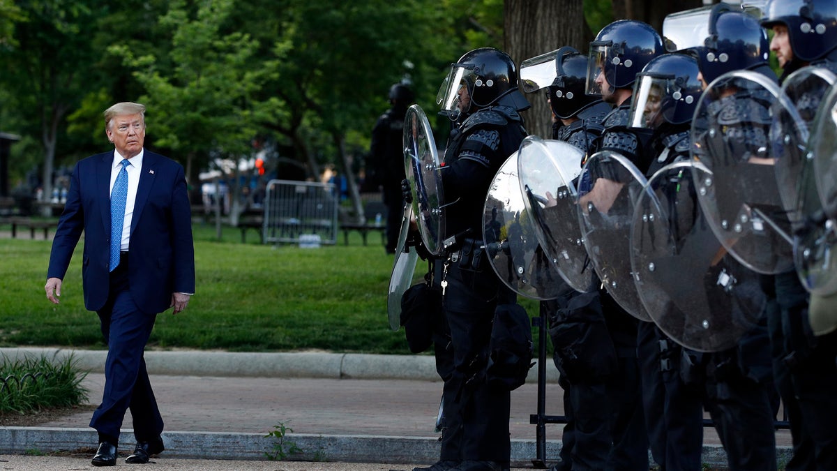 President Donald Trump walks past police in Lafayette Park after he visited outside St. John's Church across from the White House Monday, June 1, 2020, in Washington. Part of the church was set on fire during protests on Sunday night. (AP Photo/Patrick Semansky)