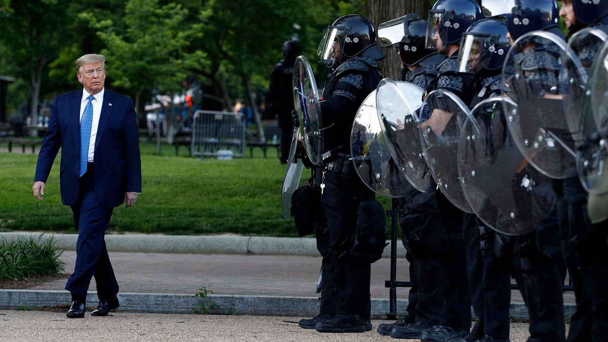 President Donald Trump walks past police in Lafayette Park after he visited outside St. John's Church across from the White House Monday, June 1, 2020, in Washington. Part of the church was set on fire during protests on Sunday night. (AP Photo/Patrick Semansky)