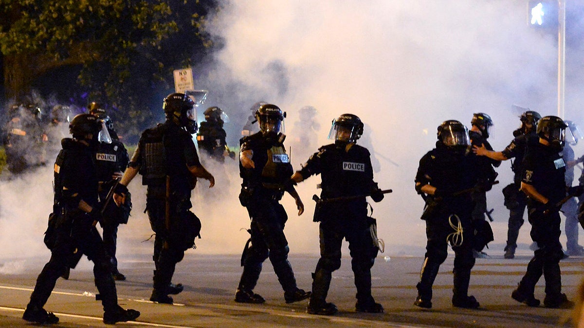 Charlotte-Mecklenburg Police Department officers begin to move forward through tear gas during a protest, Saturday, May 30, 2020, in Charlotte, N.C., as people nationwide protested the Memorial Day death of George Floyd, who died in police custody in Minneapolis. (Jeff Siner/The Charlotte Observer via AP)