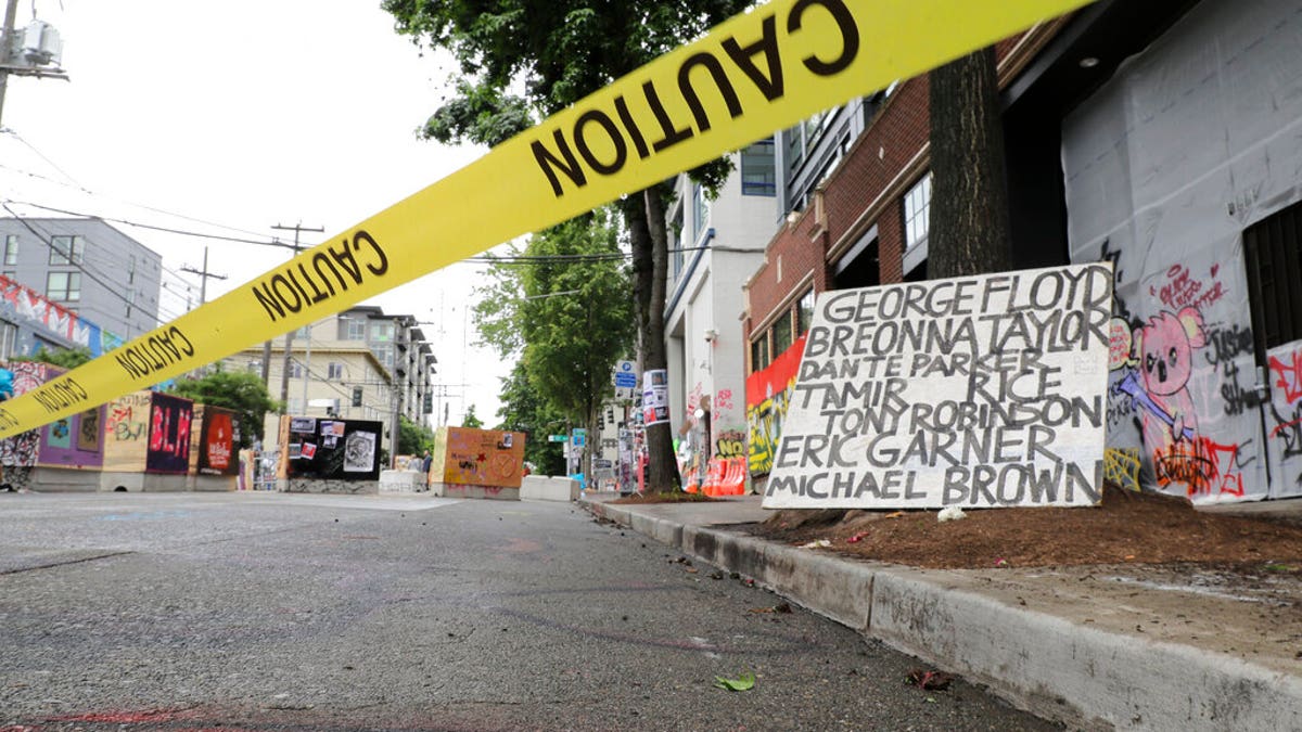Caution tape is shown near a sign with the names of victims of police violence, Saturday, June 20, 2020, at the Capitol Hill Occupied Protest zone in Seattle. 