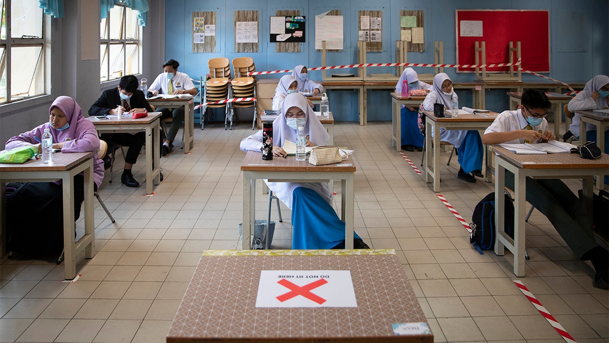 Students wearing face masks and maintaining social distancing at a classroom during the first day of school reopening at a high school in Putrajaya, Malaysia, Wednesday, June 24, 2020. Malaysia began reopening schools Wednesday while entering the Recovery Movement Control Order (RMCO) after three months of coronavirus restrictions. (AP Photo/Vincent Thian)