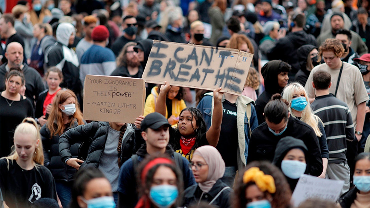 Demonstrators hold placards during a march in central Auckland, New Zealand, Monday, June 1, 2020, to protest the death of United States' George Floyd, a black man who died in police custody in Minneapolis on May 25. Floyd, who after a white police officer who is now charged with murder, Derek Chauvin, pressed his knee into Floyd's neck for several minutes even after he stopped moving and pleading for air. (Dean Purcell/New Zealand Herald via AP)