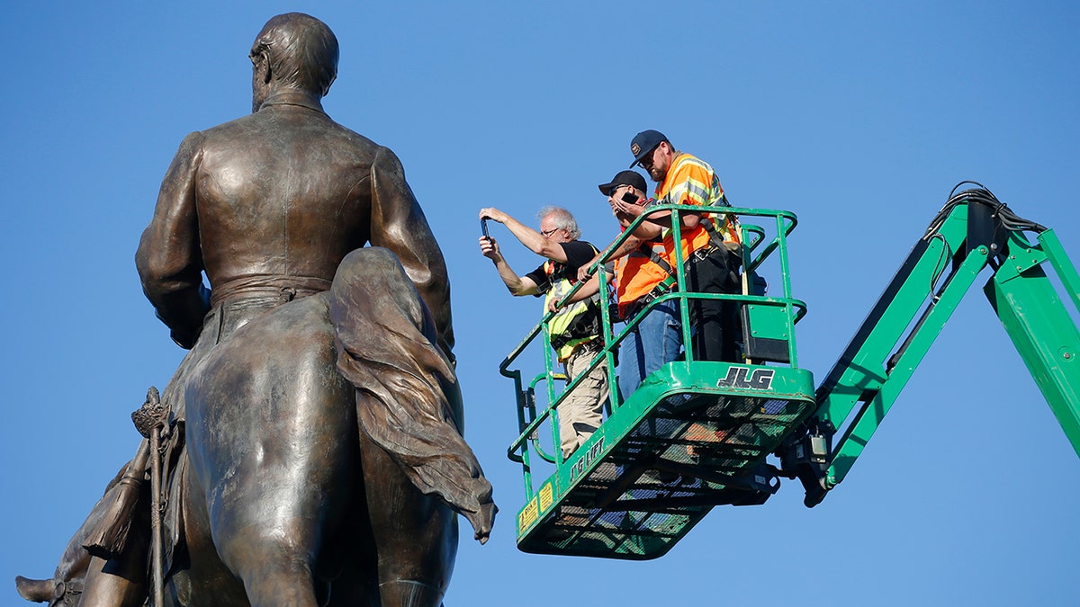 An inspection crew from the Virginia Department of General Services inspect the statue of Confederate Gen. Robert E. Lee on Monument Avenue June 8, in Richmond, Va. Virginia Gov. Ralph Northam has ordered the removal of the statue. (AP Photo/Steve Helber)