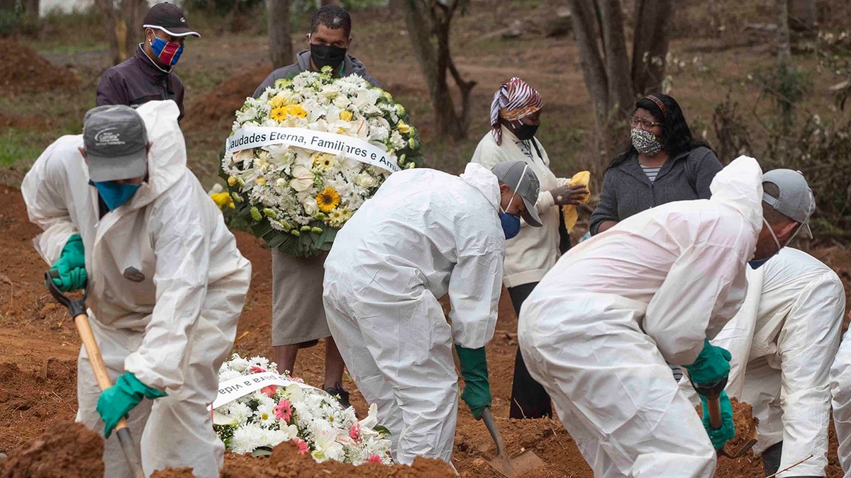 Relatives watch cemetery workers shovel dirt over the coffin of 47-year-old Paulo Roberto da Silva, who died of COVID-19, at the Sao Luiz cemetery in Sao Paulo, Brazil, Thursday, June 4, 2020. (AP Photo/Andre Penner)