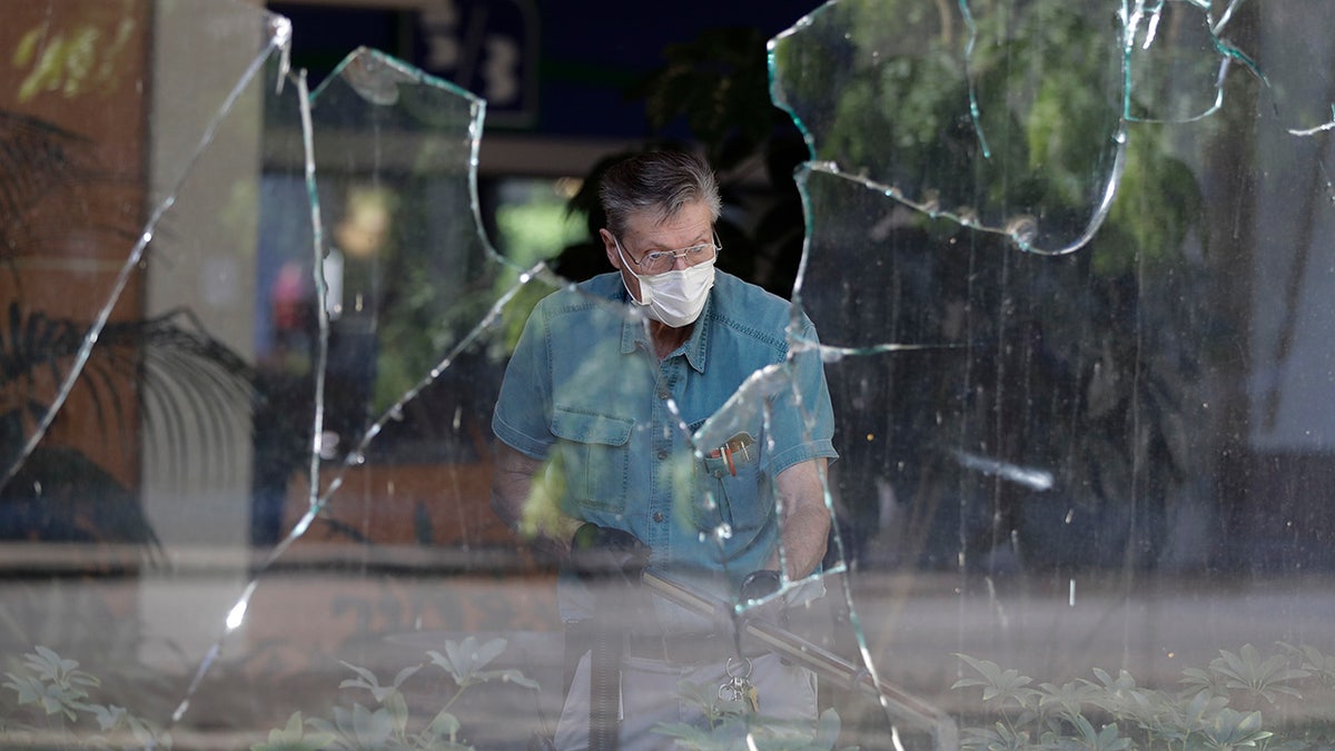 A worker vacuums broken glass from storefront in downtown Louisville, Ky. , Saturday, May 30, 2020. The store was damaged Friday evening during a protest over the deaths of George Floyd and Breonna Taylor. (AP Photo/Darron Cummings)