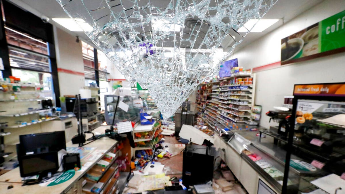 Shattered glass hangs from the doorway of a 7-Eleven store May 31, 2020, in Chicago. (AP Photo/Charles Rex Arbogast)