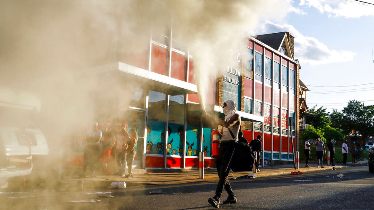 A person shoots a fire extinguisher into the air as he walks though a street in Upper Darby, Pa. on Sunday May 31, 2020, as people move through streets in protest over the death of George Floyd, a black man who was in police custody in Minneapolis. Floyd died after being restrained by Minneapolis police officers on Memorial Day, May 25. (AP Photo/Matt Slocum)