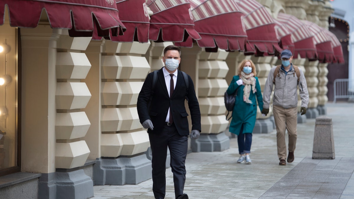 People wearing face masks and gloves to protect from coronavirus, walk to an entrance of the GUM, State Department store after reopening in Moscow, Russia, on Monday, June 1, 2020. Monday's reopening of retail stores along with dry cleaners and repair shops comes as the pace of contagion has stabilized in the Russian capital that has accounted for about half of the nation's infections. 