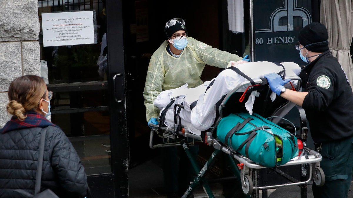 A patient is wheeled into Cobble Hill Health Center by emergency medical workers in the Brooklyn borough of New York on April 17, 2020. (AP Photo/John Minchillo, File)