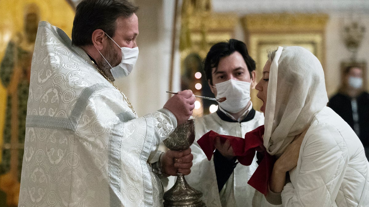 An Orthodox priest wearing a face mask to protect against coronavirus distributes Holy Communion during a service at the Christ the Savior Cathedral in Moscow, Russia, Tuesday, June 2, 2020. Churches in Moscow reopen to believers after a two-month lockdown imposed to control the spread of the coronavirus. (AP Photo/Pavel Golovkin)