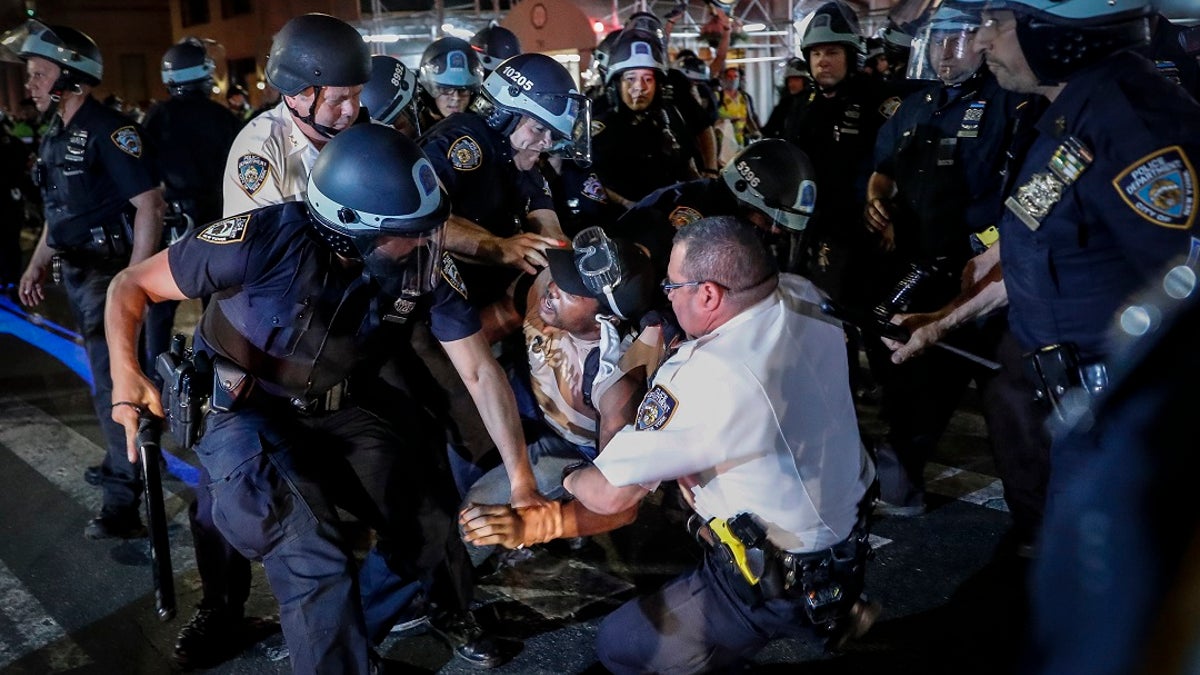 A protester is arrested on Fifth Avenue by NYPD officers during a march last week in the Manhattan. (AP Photo/John Minchillo)