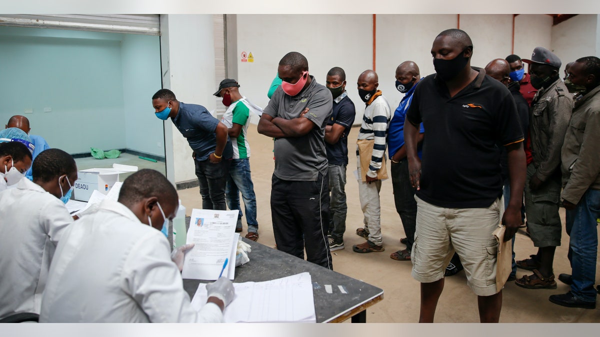 In this photo taken Monday, June 1, 2020, truck drivers entering Kenya queue to be tested for the coronavirus on the Kenya side of the Namanga border crossing with Tanzania. Africa's long-haul truckers carry food, fuel and other essential supplies along dangerous roads, but now they say they are increasingly accused of carrying the coronavirus as well. The drivers say they are stigmatized and even threatened in some countries. (AP Photo/Brian Inganga)