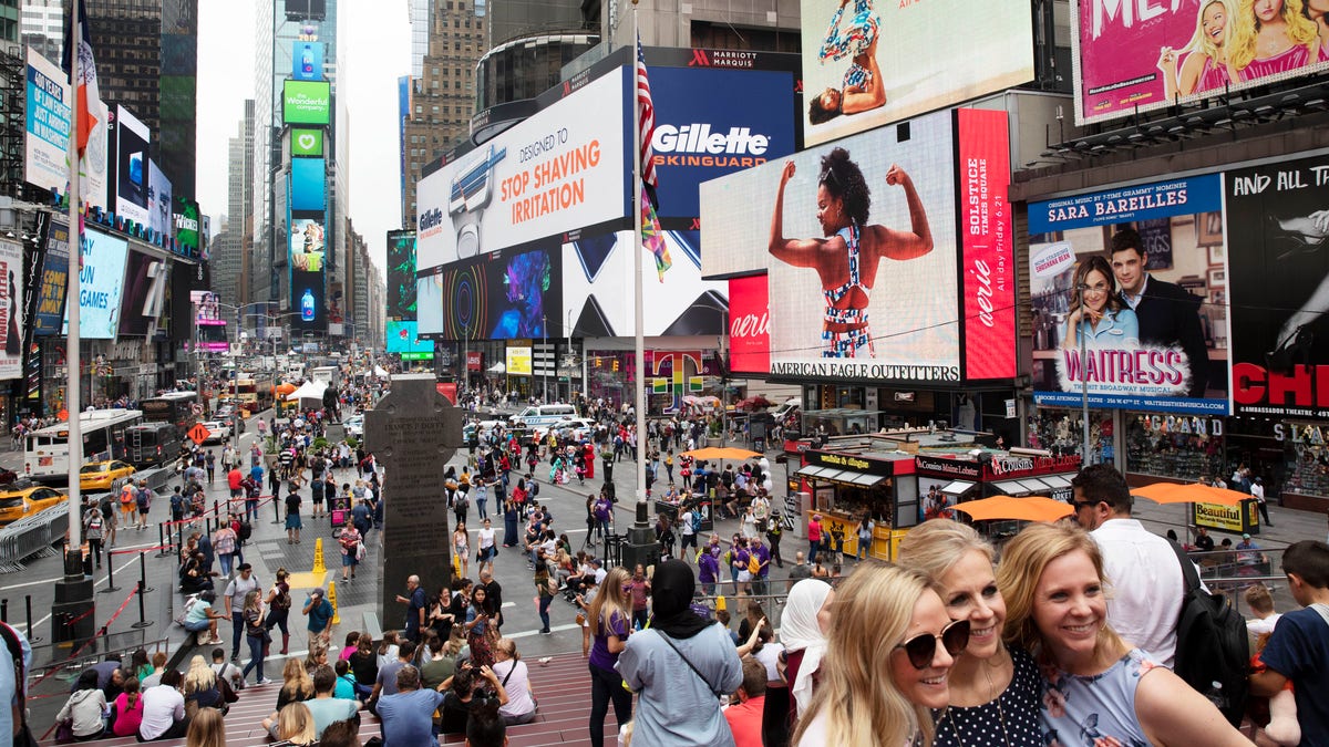 In this June 20, 2019, file photo, tourists visit Times Square in New York. After three months of a coronavirus crisis followed by protests and unrest, New York City is trying to turn a page when a limited range of industries reopen Monday, June 8, 2020. (AP Photo/Mark Lennihan, File)