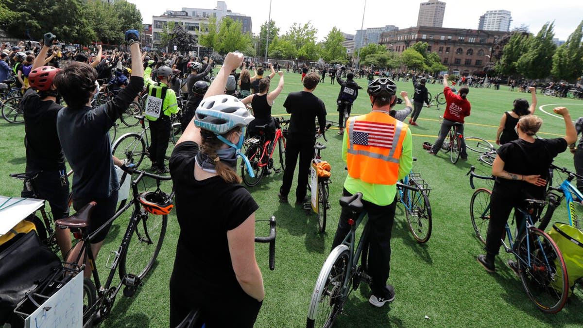 Cyclists raise their fists as they gather at Cal Anderson Park after taking part in the "Ride for Justice," Thursday, June 11, 2020, Seattle. People rode to the park and then took part in a rally to protest against police brutality and racial inequality.