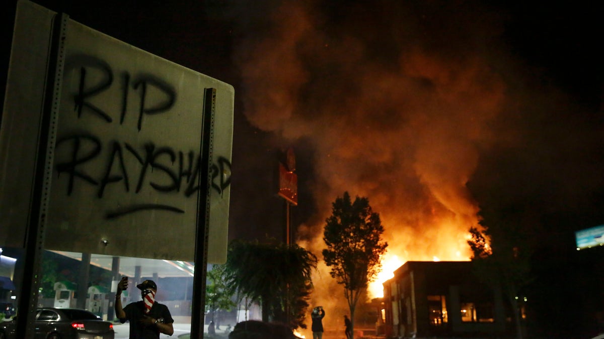 "RIP Rayshard" is spray painted on a sign as as flames engulf a Wendy's restaurant during protests Saturday, June 13, 2020, in Atlanta. The restaurant was where Rayshard Brooks was shot and killed by police Friday evening following a struggle in the restaurant's drive-thru line. (Associated Press)