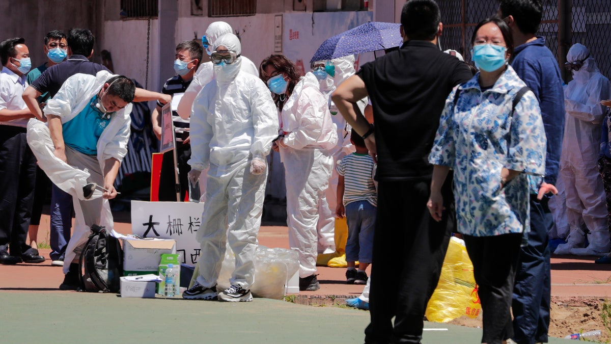 Workers put on protective suits as they wait for people living surrounding the Xinfadi wholesale market arrive to get a nucleic acid test at a stadium in Beijing, Sunday, June 14, 2020. China is reporting its highest daily total of coronavirus cases in two months after the capital's biggest wholesale food market was shut down following a resurgence in local infections. (AP Photo/Andy Wong)
