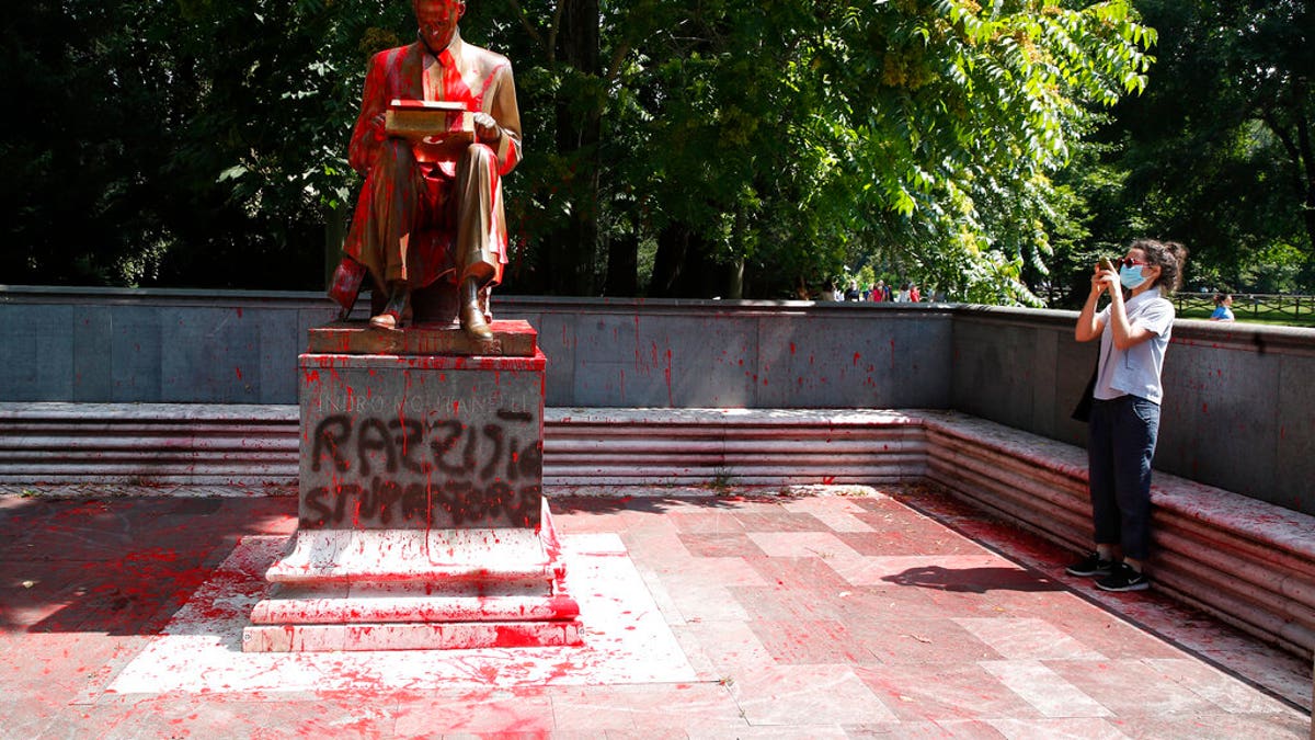 The statue of late journalist Indro Montanelli was defaced with red paint and spray-painted Italian words reading "racist," top, and "rapist," inside a park in Milan.