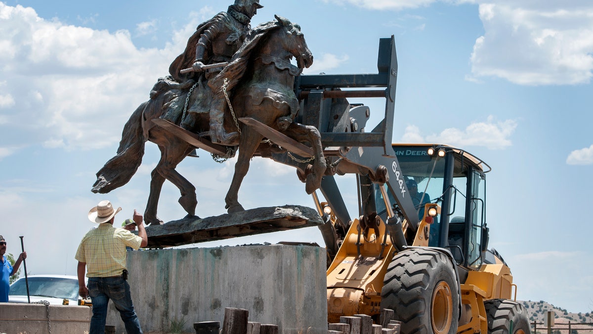 Rio Arriba County workers remove the bronze statue of Spanish conqueror Juan de Oñate from its pedestal in front of a cultural center in Alcalde, N.M., Monday, June 15, 2020. Crowds of people for and against the removal lined Highway 68 near the center. (Eddie Moore/The Albuquerque Journal via AP)