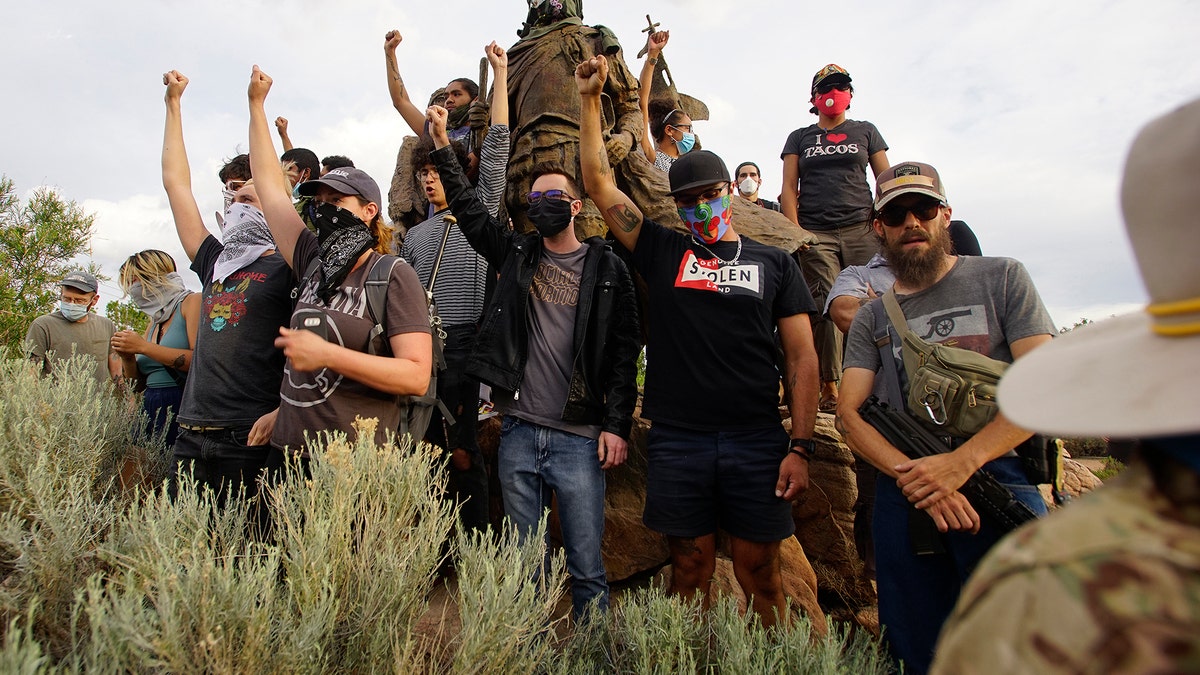 Demonstrators climb the statue of Don Juan de Onate in Old Town in Albuquerque, N.M. (Adolphe Pierre-Louis/The Albuquerque Journal via AP)