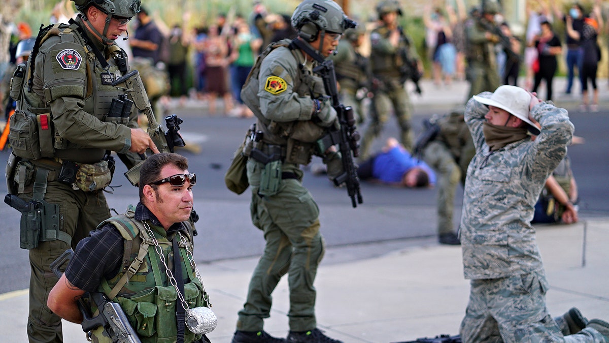 Albuquerque police detain members of the New Mexico Civil Guard, an armed civilian group, following the shooting of a man during a protest over a statue of Spanish conquerer Juan de Oñate on Monday, June 15, 2020, in Albuquerque, N.M. (Adolphe Pierre-Louis/The Albuquerque Journal via AP)