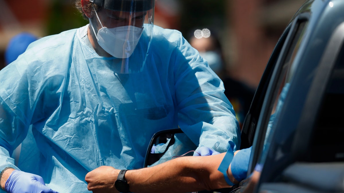 A health worker draws blood for COVID-19 antibody testing in Dearborn, Mich on June 12, 2020. A genetic analysis of COVID-19 patients published Wednesday the New England Journal of Medicine suggests a person's blood type may have some influence on whether they develop severe disease. (AP Photo/Paul Sancya, File)