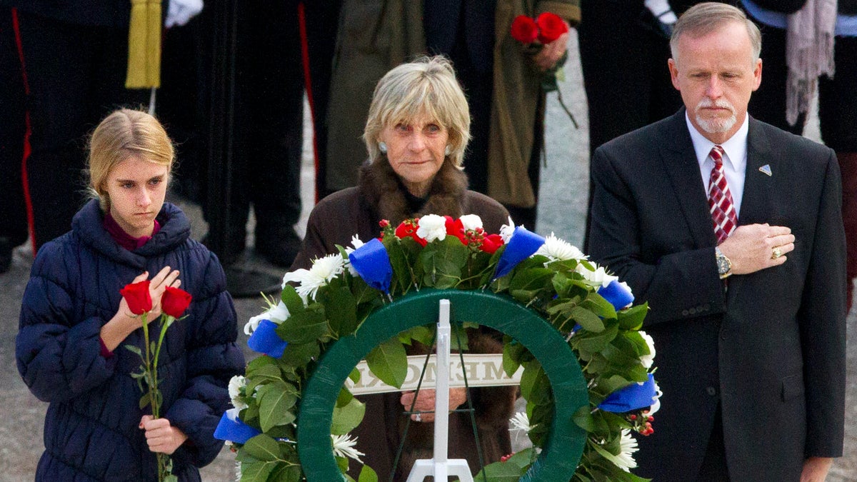 FILE - In this Nov. 22, 2013 file photo, An unidentified girl, left, holds a rose during a wreath laying ceremony with former Ambassador to Ireland Jean Kennedy Smith, center, and Patrick Hallinan, executive director of Army National Military Cemeteries, at the grave of John F. Kennedy at Arlington National Cemetery, in Arlington, Va. Jean Kennedy Smith, the youngest sister and last surviving sibling of President John F. Kennedy, died at 92, her daughter confirmed to The New York Times, Wednesday, June 17, 2020. (AP Photo/Jacquelyn Martin)