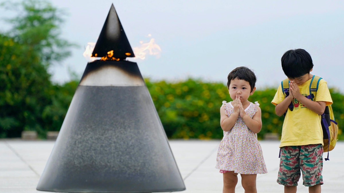 Children pray in front of the "Peace of Fire" at the Peace Memorial Park in Itoman, Okinawa, Japan, Tuesday, June 23, 2020. (Koji Harada/Kyodo News via AP)