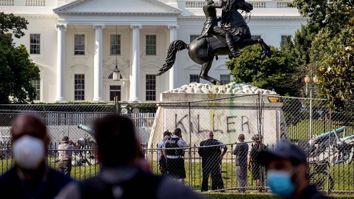 The White House is visible behind a statue of President Andrew Jackson in Lafayette Park on Tuesday in Washington, with the word "Killer" spray-painted on its base. Protesters tried to topple the statue Monday night. (AP Photo/Andrew Harnik)