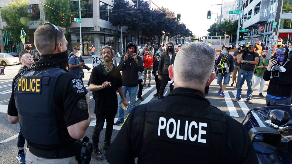 Seattle Police officers are confronted by protesters, Friday, June 26, 2020 just outside a barricade at the CHOP (Capitol Hill Occupied Protest) zone in Seattle after Seattle Department of Transportation workers arrived with the intention of removing barricades that had been set up in the area, which has been occupied by protesters since Seattle Police pulled back from their East Precinct building following violent clashes with demonstrators earlier in the month. 