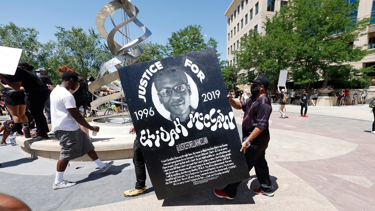 Demonstrators carry a giant placard during a rally and march over the death of 23-year-old Elijah McClain on Saturday outside the police department in Aurora, Colo. McClain died in late August 2019 after he was stopped while walking to his apartment by three Aurora Police Department officers. (AP Photo/David Zalubowski)