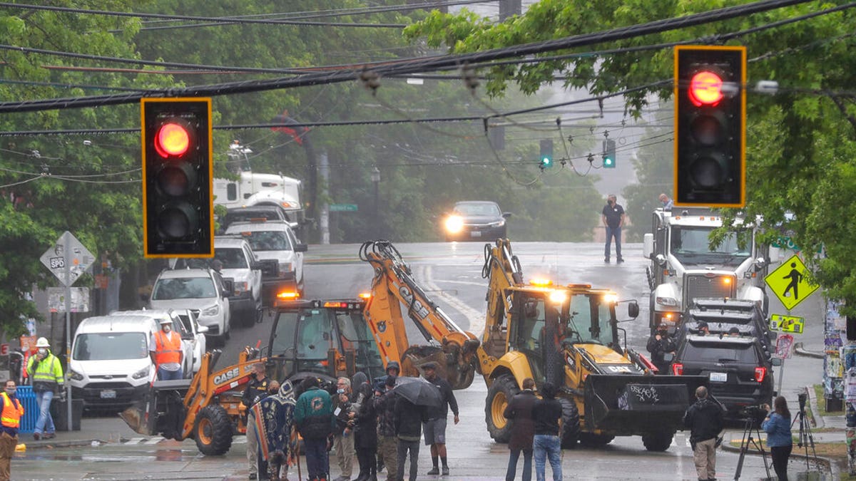 Seattle Department of Transportation workers remove barricades at the intersection of 10th Ave. and Pine St. on Tuesday at the CHOP zone in Seattle. Protesters quickly moved couches, trash cans and other materials in to replace the cleared barricades. (AP Photo/Ted S. Warren)